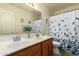 Bathroom features a double vanity, large mirror, and a shower-tub combo with a leafy shower curtain at 11318 S Hopi Dr, Goodyear, AZ 85338