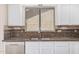 Close-up of a kitchen sink and counter area with white cabinets and tiled backsplash at 11318 S Hopi Dr, Goodyear, AZ 85338