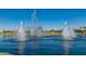 Scenic lake view featuring fountains, lush greenery, and a clear blue sky at 11318 S Hopi Dr, Goodyear, AZ 85338