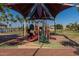 Colorful playground under a shaded canopy, surrounded by palm trees and open space at 11318 S Hopi Dr, Goodyear, AZ 85338