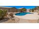 Backyard featuring a uniquely shaped private pool surrounded by desert landscaping and rock features at 11318 S Hopi Dr, Goodyear, AZ 85338