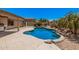 A backyard oasis featuring a freeform pool surrounded by lush greenery and desert landscaping at 11318 S Hopi Dr, Goodyear, AZ 85338