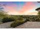 Lush backyard with a fire pit, desert landscaping, and serene mountain views at sunset at 11988 E Larkspur Dr, Scottsdale, AZ 85259
