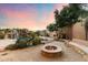 Outdoor space with a pool and waterfall, fire pit, fireplace, and lush desert landscaping at 11988 E Larkspur Dr, Scottsdale, AZ 85259