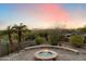 Charming backyard featuring a stone fire pit, desert plants, and views of the surrounding desert landscape at 11988 E Larkspur Dr, Scottsdale, AZ 85259