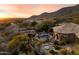 Expansive backyard featuring a pool, fire pit, lush landscaping, and stunning mountain views at sunset at 11988 E Larkspur Dr, Scottsdale, AZ 85259