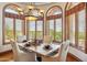 Dining room with wooden table, upholstered chairs, chandelier, and views through arched windows at 11988 E Larkspur Dr, Scottsdale, AZ 85259