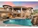 Stunning home exterior showcasing a covered patio, pool with a waterfall feature, and desert landscaping at sunset at 11988 E Larkspur Dr, Scottsdale, AZ 85259