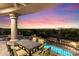 Back patio with dining set overlooking the pool with cascading rock waterfall and city lights at 11988 E Larkspur Dr, Scottsdale, AZ 85259