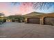 Three-car garage with stone details and ample parking space situated in a serene desert setting at 11988 E Larkspur Dr, Scottsdale, AZ 85259