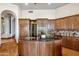 Kitchen with a granite countertop island, wood cabinets and a step-up to another living space at 11988 E Larkspur Dr, Scottsdale, AZ 85259