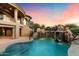Luxurious backyard featuring a pool with waterfalls, lush greenery, and an outdoor kitchen perfect for entertaining at 11988 E Larkspur Dr, Scottsdale, AZ 85259