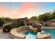 Inviting backyard pool with rock waterfall feature, and spa surrounded by desert landscaping at 11988 E Larkspur Dr, Scottsdale, AZ 85259