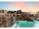 Backyard pool features a stone waterfall feature, lush landscaping, and cool blue water at 11988 E Larkspur Dr, Scottsdale, AZ 85259