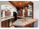 Basement wet bar area with granite countertops, custom cabinetry, and copper-style ceiling tiles at 11988 E Larkspur Dr, Scottsdale, AZ 85259
