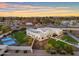 Stunning aerial view of a modern white home, basketball court, and landscaped backyard at sunset at 12034 N 61St St, Scottsdale, AZ 85254
