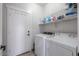 Bright laundry area featuring a washer, dryer, storage shelves, and a convenient hanging rack at 1629 E Prickly Pear Pl, Casa Grande, AZ 85122