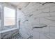 Modern shower featuring elegant marble-style tiling, a built-in bench, and stylish fixtures at 1629 E Prickly Pear Pl, Casa Grande, AZ 85122