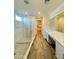 Bathroom featuring a marble walk-in shower, double vanity, and wood-look tile flooring at 17168 W Middlebury St, Surprise, AZ 85388