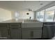 Kitchen island featuring a farmhouse sink and stainless steel dishwasher and views to the living room and sliding glass doors at 17168 W Middlebury St, Surprise, AZ 85388