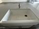 Close-up of a farmhouse style kitchen sink with modern faucet, set into a white countertop with complementary cabinetry below at 17168 W Middlebury St, Surprise, AZ 85388