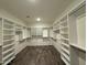 A large walk-in closet with custom white shelves and wood-style tile flooring at 17168 W Middlebury St, Surprise, AZ 85388