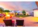 A backyard with paver patio, fire pit, and artificial lawn for low maintenance enjoyment at 18322 W Thistle Landing Dr, Goodyear, AZ 85338