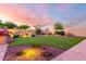 Landscaped backyard featuring artificial turf, rock waterfall feature, desert landscaping, and charming hardscape at 18322 W Thistle Landing Dr, Goodyear, AZ 85338