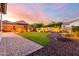 Paver patio leading to a lush backyard with artificial grass, rock waterfall, and fire pit at 18322 W Thistle Landing Dr, Goodyear, AZ 85338