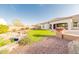 Lush backyard with artificial turf, rock features, desert landscaping and a covered patio at 18322 W Thistle Landing Dr, Goodyear, AZ 85338