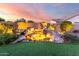 Beautiful backyard featuring an illuminated rock waterfall, lush plants and artificial grass at 18322 W Thistle Landing Dr, Goodyear, AZ 85338