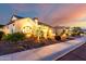 Charming single-story home exterior with tiled roof, neutral stucco, tasteful front landscaping, and warm accent lighting at 18322 W Thistle Landing Dr, Goodyear, AZ 85338