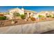 Beautiful home with desert landscaping, featuring mature trees, flowering plants, and stone accents at 18322 W Thistle Landing Dr, Goodyear, AZ 85338