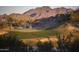 Scenic golf course featuring lush green with desert vegetation, sand traps, and mountain views at 18322 W Thistle Landing Dr, Goodyear, AZ 85338