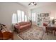 Bright living room featuring an arched window, shutters, and decorative shelving at 18322 W Thistle Landing Dr, Goodyear, AZ 85338