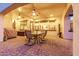 Covered patio featuring a dining table, ceiling fans, and views of the landscaped backyard and interior at 18322 W Thistle Landing Dr, Goodyear, AZ 85338