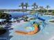 Resort-style community pool with splash pad, waterslide, lounge seating and lush palm trees at 18322 W Thistle Landing Dr, Goodyear, AZ 85338
