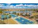 This aerial shot showcases the basketball and tennis courts, palm trees and play areas in a lakefront park at 18322 W Thistle Landing Dr, Goodyear, AZ 85338