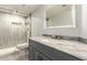 Bathroom with tiled shower, gray vanity, and a sleek, framed mirror at 18860 N 73Rd Dr, Glendale, AZ 85308