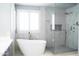 Bright bathroom featuring a soaking tub, shower with glass surround, marble flooring, and plantation shutters at 18860 N 73Rd Dr, Glendale, AZ 85308
