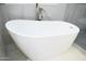 Close up of freestanding white soaking tub with modern faucet set against marble tile at 18860 N 73Rd Dr, Glendale, AZ 85308