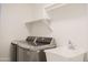 Clean laundry room features a utility sink, overhead shelving and front-loading, gray washer and dryer at 18860 N 73Rd Dr, Glendale, AZ 85308