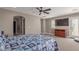 Spacious bedroom with a ceiling fan, large TV, arched doorway, and light-filled door leading outside at 20539 W Terrace Ln, Buckeye, AZ 85396