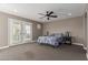 The bedroom has light beige walls and carpet, ceiling fan and light-filled French doors leading outside at 20539 W Terrace Ln, Buckeye, AZ 85396