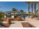 Community pool with palm trees, colorful flowers, blue lounge chairs, and covered patio at 20539 W Terrace Ln, Buckeye, AZ 85396