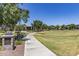 Well-maintained sidewalk through a grassy area with trees and benches for relaxation at 20539 W Terrace Ln, Buckeye, AZ 85396
