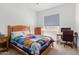 Cozy bedroom with a wooden bed frame, charming quilt, and a desk setup by the bright window at 21165 E Thornton Rd, Queen Creek, AZ 85142