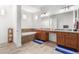 Well-lit bathroom with large tub, dual sink vanity, and warm wood cabinetry at 21165 E Thornton Rd, Queen Creek, AZ 85142