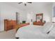 Spacious bedroom with wood furniture set, ceiling fan and views of the ensuite bathroom at 21165 E Thornton Rd, Queen Creek, AZ 85142