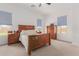 Bright bedroom with wood furniture set, ceiling fan, and natural light from two windows at 21165 E Thornton Rd, Queen Creek, AZ 85142
